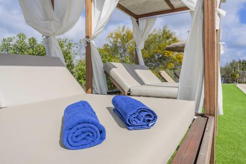 a bed with two blue towels and two chairs at E227 Sa Pedrera by Mallorca Villa Selection in Caʼs Concos