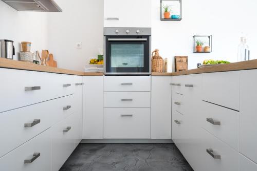 a kitchen with white cabinets and a microwave at Hiša sonca Toti breg in Svečina