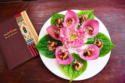 a plate of food with flowers and a book at Ban Rai Jai Chaem - Spa Cafe & Homestay in Ban Rai