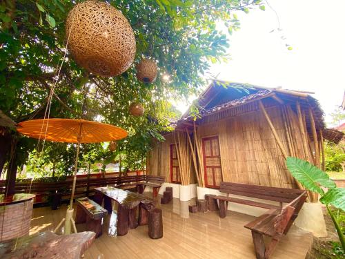 a house with benches and an umbrella in front of it at Ban Rai Jai Chaem - Spa Cafe & Homestay in Ban Rai