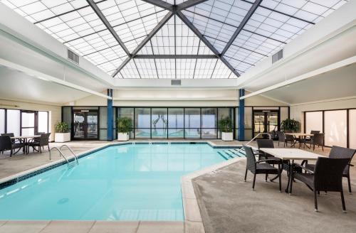 uma grande piscina com mesas e cadeiras e um grande tecto de vidro em Crowne Plaza Providence-Warwick (Airport), an IHG Hotel em Warwick