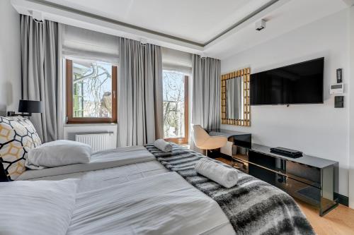 a bedroom with a large bed and a flat screen tv at Premium Apartment with Sauna by Grand Apartments in Sopot