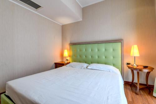 a bedroom with a large bed with a green headboard at Hotel Master in Brescia