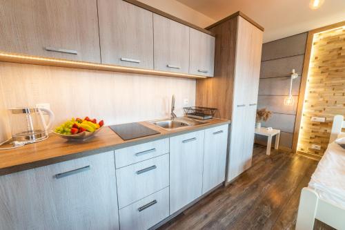 a kitchen with white cabinets and a bowl of fruit on the counter at Promenada Apartamenty i Domek Nad Jeziorem in Mikołajki