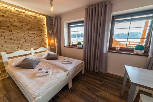 a bedroom with a bed and a table and windows at Promenada Apartamenty i Domek Nad Jeziorem in Mikołajki
