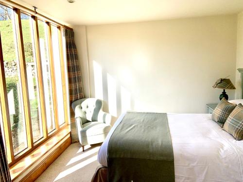 a bedroom with a bed and a chair and windows at The Sportsman's Arms in Harrogate