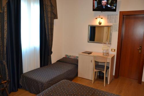 a small room with a bed and a desk with a mirror at Hotel Caravelle&MiniCaravelle in Lido di Jesolo