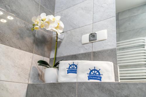 a bathroom with white towels and a flower in a vase at Promenada Apartamenty i Domek Nad Jeziorem in Mikołajki