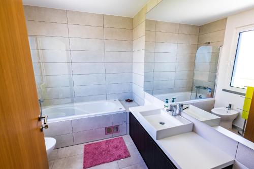 ein Badezimmer mit einer Badewanne, einem Waschbecken und einer Badewanne in der Unterkunft Sun and Sea II in Caniço