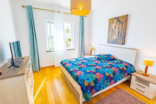 Schlafzimmer mit einem Bett mit blauer Decke in der Unterkunft Sun and Sea II in Caniço