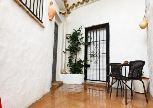 a patio with two chairs and a door with a plant at Ojalá... in Vejer de la Frontera