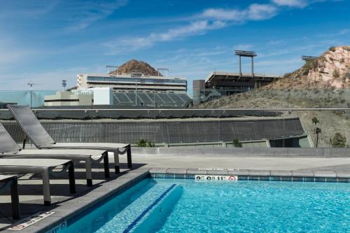a swimming pool with two chairs and a building at Hyatt House Tempe Phoenix University in Tempe