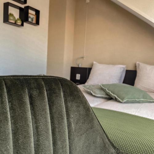 een bed met groene en witte kussens in een kamer bij B&B Mol in Katwijk aan Zee