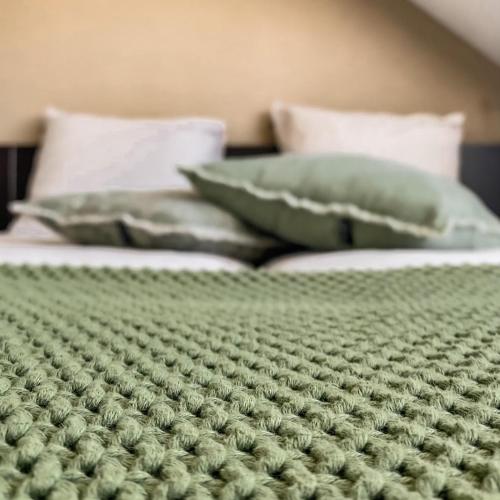 2 camas con edredones y almohadas verdes en B&B Mol, en Katwijk aan Zee