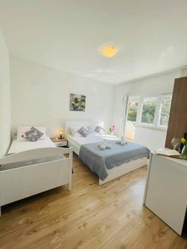two beds in a white room with wooden floors at Apartman & rooms Draga in Marina