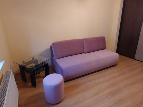 a living room with a purple couch and a table at Apartament Przy Kortach in Bytom