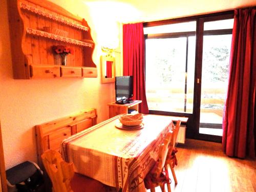 a dining room with a table and a television at Résidence Chanteneige - Freeloc Immobilier in Les Menuires