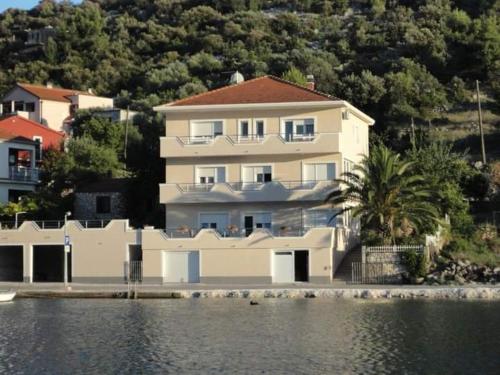 a large white house next to a body of water at Apartman & rooms Draga in Marina