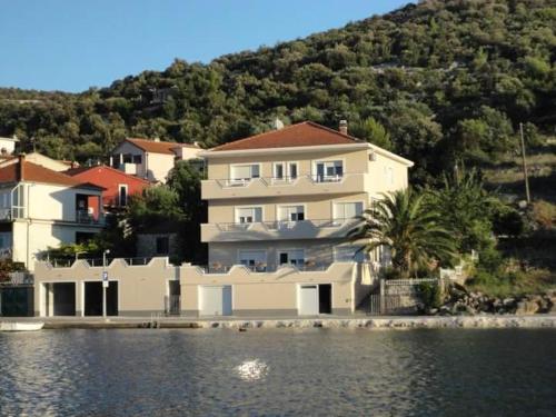 a large white house next to a body of water at Apartman & rooms Draga in Marina