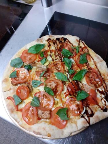 a pizza with tomatoes and basil on a table at L'ANGOLO DEI SAPORI in Rueun