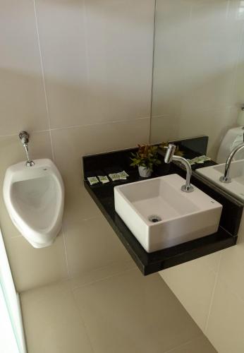 a bathroom with a white sink and a urinal at Pousada Elo Inn in Recife