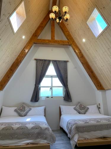 two beds in a attic room with a window at 維瓦利 in Sanxing