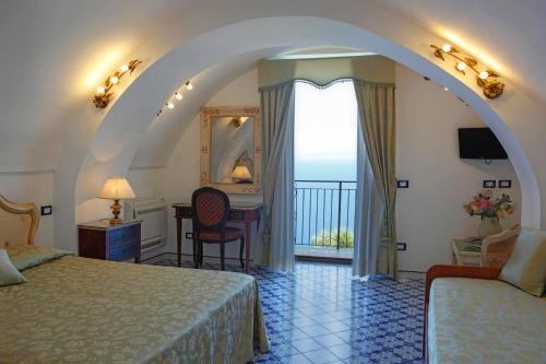a hotel room with a bed and a desk and a window at Villa Borgo San Michele in Amalfi