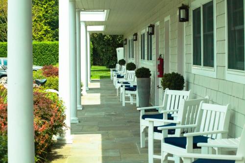 une rangée de chaises à bascule blanches sur une maison dans l'établissement Southampton Village Motel, à Southampton