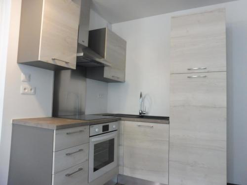 a kitchen with white cabinets and a stove top oven at Studio de charme au centre ville in Salies-de-Béarn