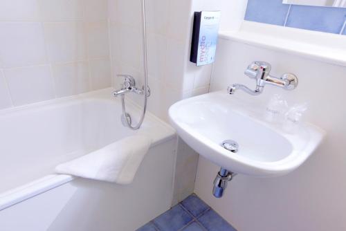 La salle de bains blanche est pourvue d'un lavabo et d'une baignoire. dans l'établissement Kyriad Direct Marseille Est La Valentine, à La Penne-sur-Huveaune