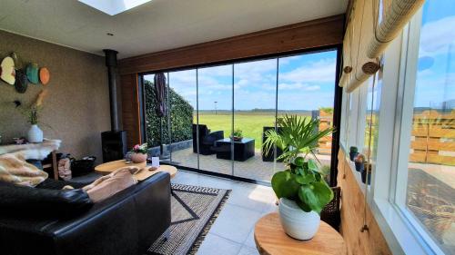 a living room with a couch and a large window at B&B Hertenhoef, Fluitenberg (Hoogeveen) in Fluitenberg