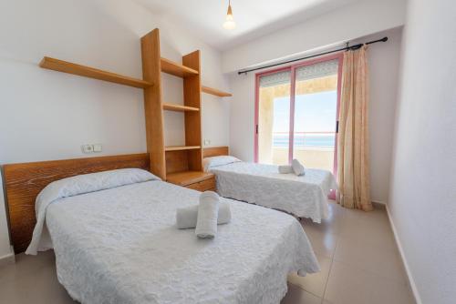 a bedroom with two beds and a window with the ocean at Apartamentos Nuevo México C 142 in Calpe
