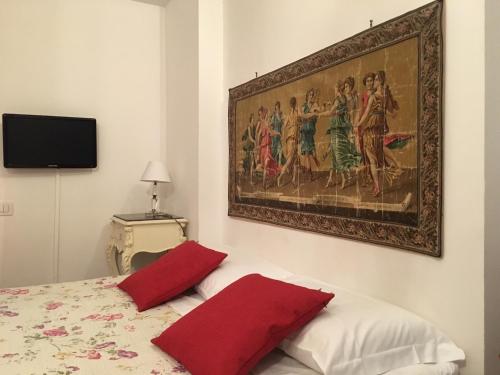 a bedroom with a painting above a bed with red pillows at Affittacamere Arco Polinori in Foligno