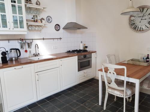a kitchen with white cabinets and a wooden table at bij Saar in Zwinderen