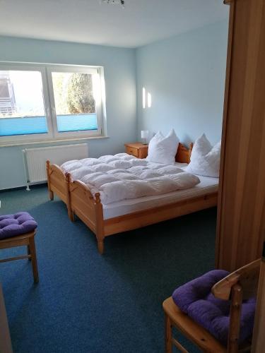 a bedroom with a large bed and two windows at Ferienwohnung 4, Waldesruh Dierhagen in Dierhagen