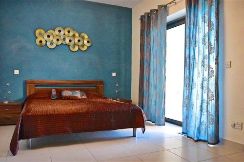 a bedroom with a bed and a blue wall at Sunny Apartment in Tas-Sellum Mellieha, Malta. in Għajn Żejtuna