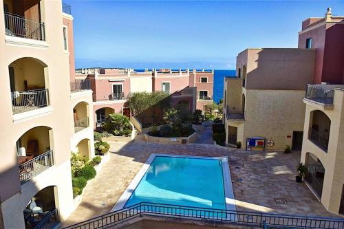 a view of a swimming pool between two buildings at Sunny Apartment in Tas-Sellum Mellieha, Malta. in Għajn Żejtuna