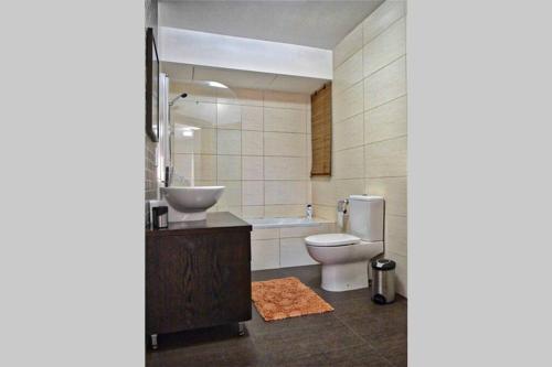 a bathroom with a toilet and a sink and a tub at Sunny Apartment in Tas-Sellum Mellieha, Malta. in Għajn Żejtuna