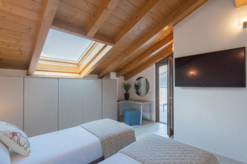 a bedroom with two beds and a tv at Dream Lake Apartments Lake View - private beach by Rent All Como in Lezzeno