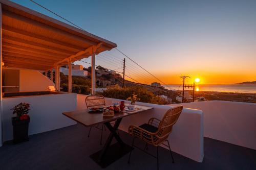 a table and chairs on a balcony with the sunset at Blue Soul Luxury Villa in Éxo Goniá