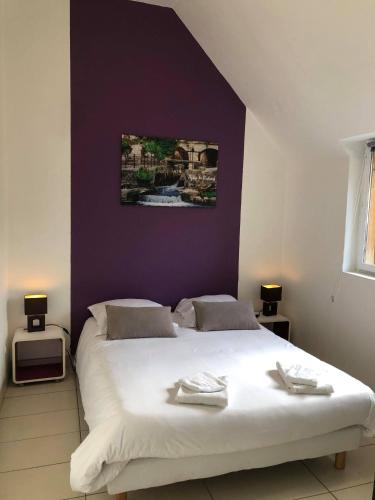 une chambre avec un lit blanc avec un mur violet dans l'établissement Chez Benjamin & Samantha - Les Portes du Château, à Azay-le-Rideau