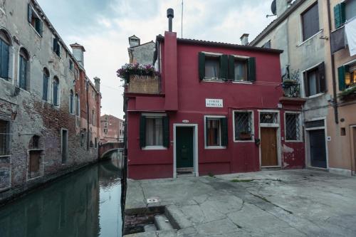 a red building next to a canal in a city at BlueYellow home in Cannaregio Air conditioning WiFi in Venice
