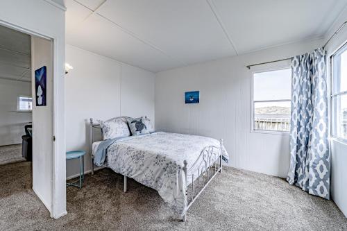 um quarto branco com uma cama e uma janela em Driftwood Cottage em Eureka