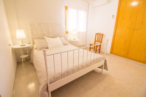 1 dormitorio con 1 cama blanca y 2 sillas en Lovely apartment a few meters from the beach, en Pollensa