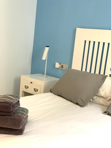 a bedroom with a white bed with a blue wall at Apartaments El Cine in Roses