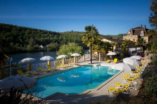 a swimming pool with chairs and umbrellas next to a river at Les Magnolias in Lalinde