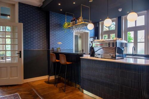 a kitchen with blue walls and a counter with stools at Boutique Hotel Het Scheepshuys in Breda