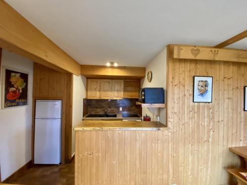 eine Küche mit Holzschränken und einem weißen Kühlschrank in der Unterkunft Le Courtis au Bourjaillet in Notre-Dame-de-Bellecombe