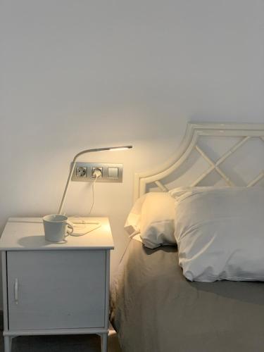 a bed with a nightstand with a cup on it at Apartaments El Cine in Roses