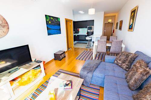 a living room with a blue couch and a flat screen tv at Sun and Sea I in Caniço